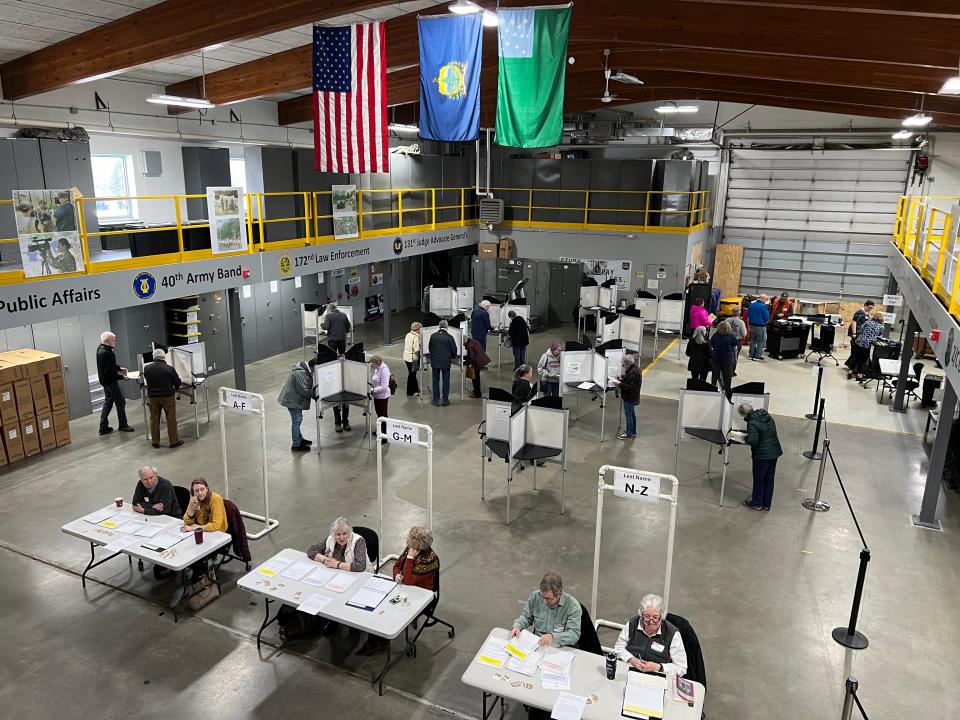 The American flag, Vermont flag and Vermont National Guard flag hang above Williston voters in the armory as they voted during Town Meeting Day and Super Tuesday on March 5, 2024.