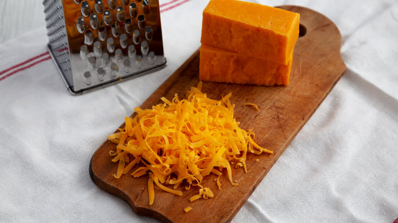 Freshly grated sharp cheddar cheese on a cutting board