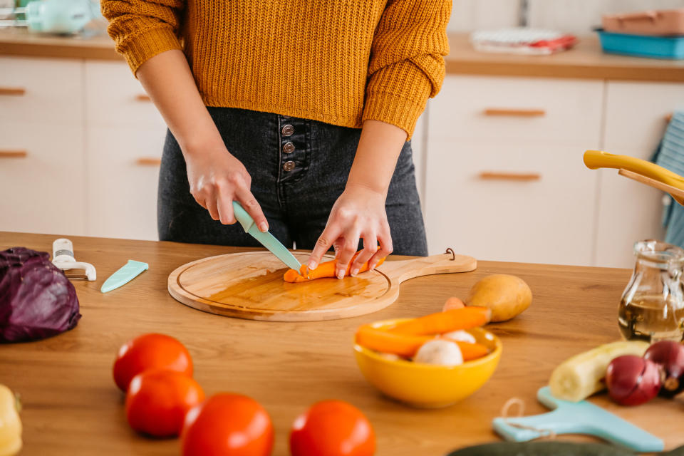 Someone chops a carrot on a counter with many different vegetables