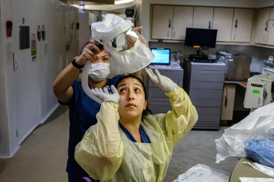 A nurse gets help putting on her personal protective equipment at Sharp Chula Vista.