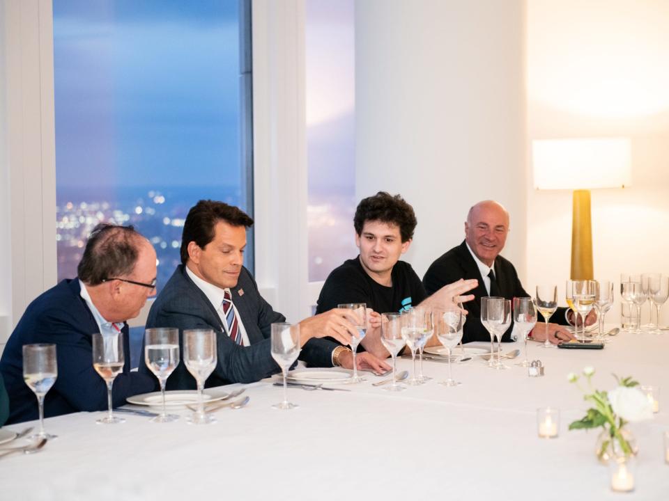 Sam Bankman-Fried is shown sitting at a long white table having dinner with Anthony Scaramucci  and Shark Tank investor Kevin O'Leary.