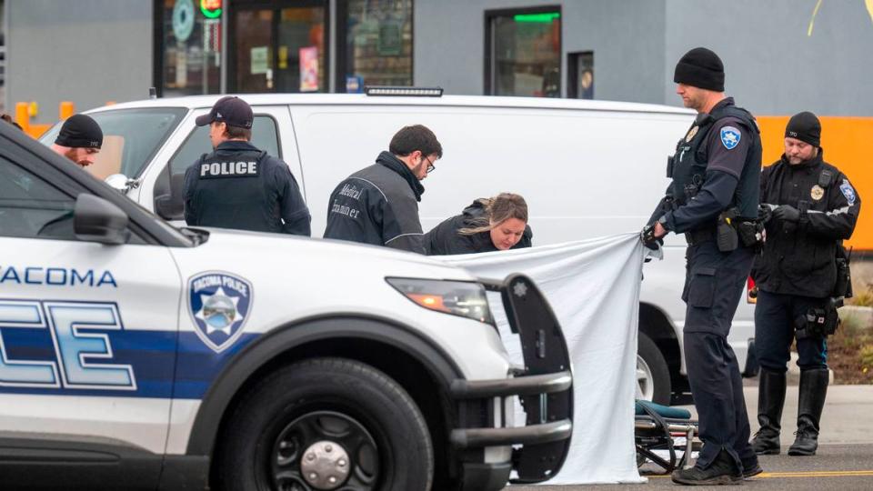 Officers from the Tacoma Police Department hold up a curtain as medical examiners investigate the scene of a pedestrian that was killed in a hit-and-run in the 8800 block of Pacific Avenue on Friday, Nov. 25, 2022, in Tacoma, Wash. The accident was reported at 6:02 a.m. Friday morning and all lanes of Pacific Avenue were closed from from 90th Street to 90th Street as the crash investigation team analyzed the scene.