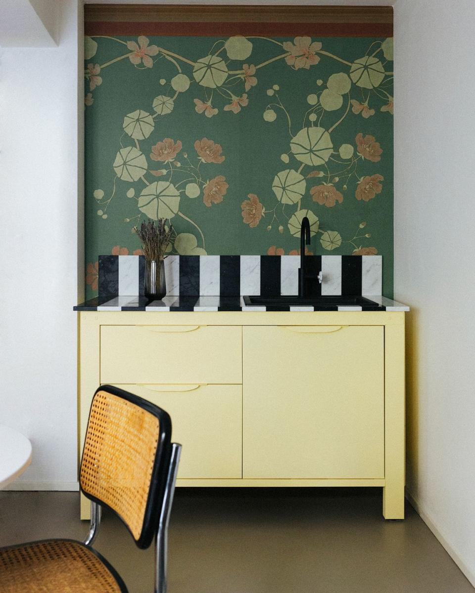 Small yellow metal kitchen cabinet with monochrome marble striped splashback