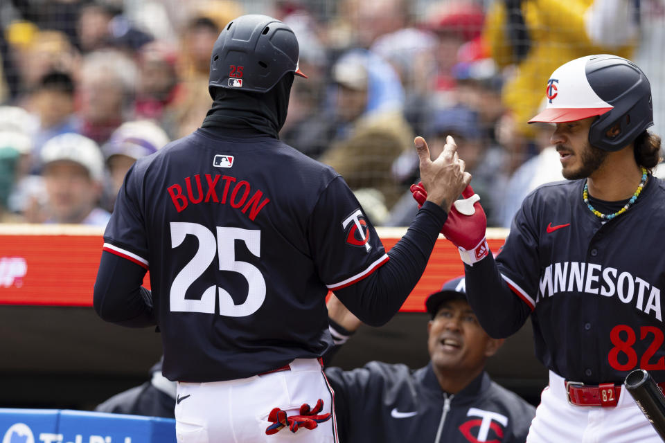 Minnesota Twins' Byron Buxton (25) high-fives Austin Martin (82) after scoring on a sacrifice fly ball hit by Willi Castro during the second inning of a baseball game against the Detroit Tigers, Saturday, April 20, 2024, in Minneapolis. (AP Photo/Stacy Bengs)