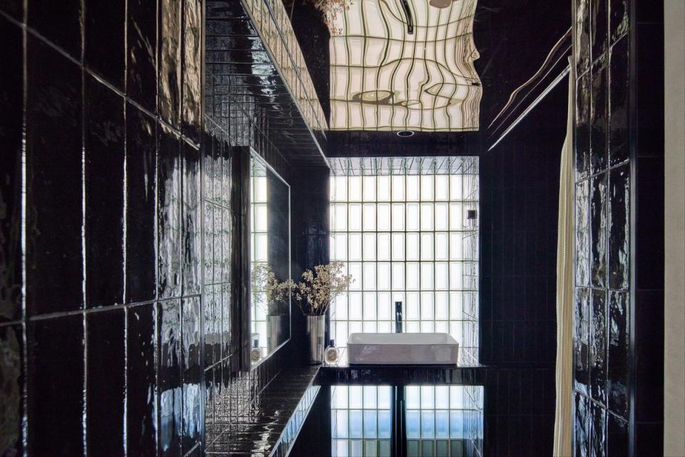 The glamorous new bathroom, lined in black metro tiles with a mirrored ceiling (Juliet Murphy)
