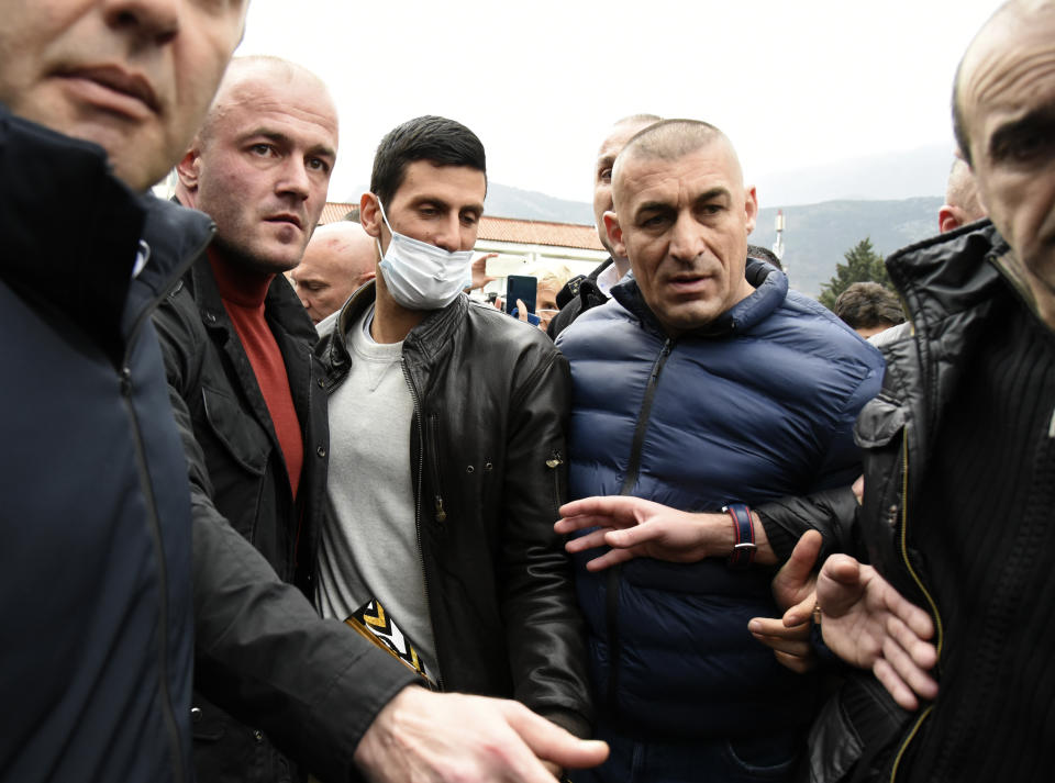 Serbian tennis player Novak Djokovic, center, with mask arrives in the municipal building in Budva, Montenegro, Friday, Jan. 28, 2022. Djokovic arrived to receive a plaque declaring him an honorary citizen of the town. (AP Photo/Risto Bozovic)