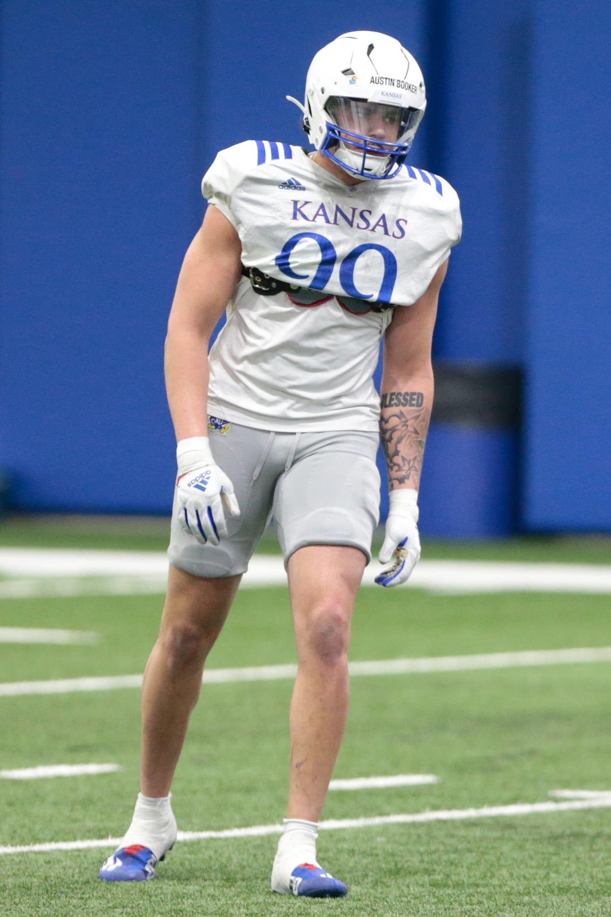 Kansas redshirt sophomore defensive end Austin Booker (99) works through drills during Tuesday's practice at the team's indoor practice facility.