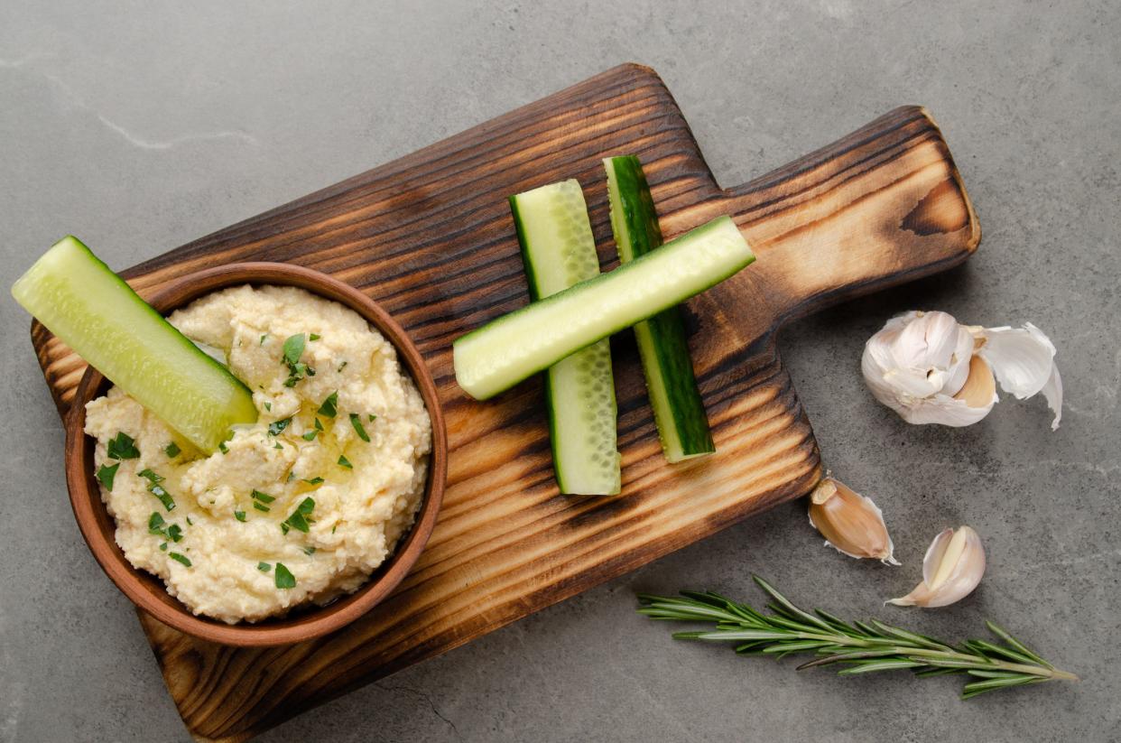 Flat lay view at vegetable Hummus dip dish topped with olive oil served with cucumber slices