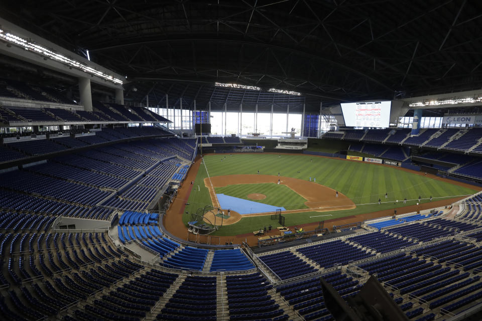 FILE - This is a July 4, 2020, file photo showing the Miami Marlins running drills during a baseball workout at Marlins Park in Miami. Marlins Park will have a new look for its 2020 season debut Friday, thanks to cozier dimensions and a switch to artificial turf. Also, the home team is in first place. (AP Photo/Wilfredo Lee, File)