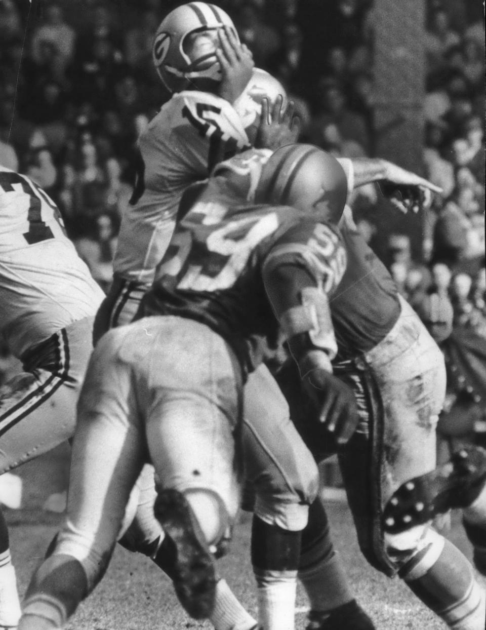 Bart Starr of the Packers gets rough treatment from a couple of Lions in the fourth quarter, seconds after tossing a pass. No. 59 is Ernie Clark.