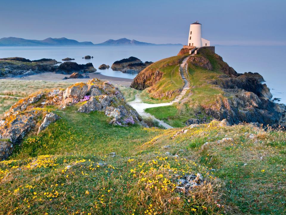 A lighthouse on the edge of Llanddwyn Island with the Mountains of The Lleyn Peninsula in the background