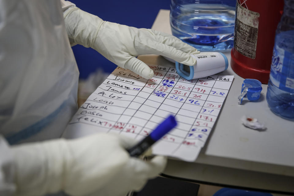 A medical worker tracks the temperature and vital signs of coronavirus patients in the intensive care unit of an isolation and treatment center for those with COVID-19 in Machakos, south of the capital Nairobi, in Kenya Tuesday, Nov. 3, 2020. As Africa is poised to surpass 2 million confirmed coronavirus cases it is Kenya's turn to worry the continent with a second surge in infections well under way. (AP Photo/Brian Inganga)