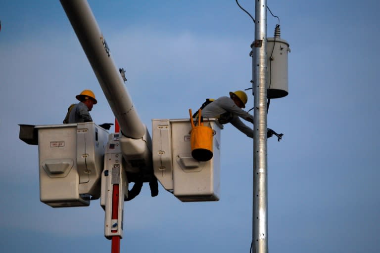 A Puerto Rico Electric and Power Authority lineman attaches an electrical insulator to a new utility pole in a residential area