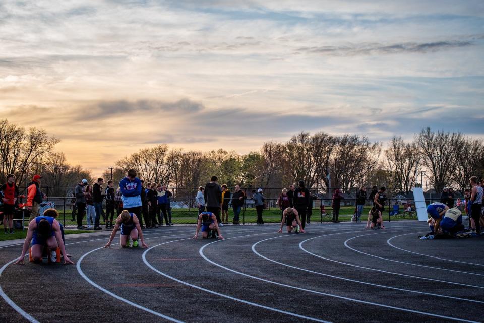 Winnebago's Michael Cunningham, fourth from the left, and the rest of the field of the 200-meter dash get set to run as the sun sets on a track and field meet at Winnebago on May 6, 2022.