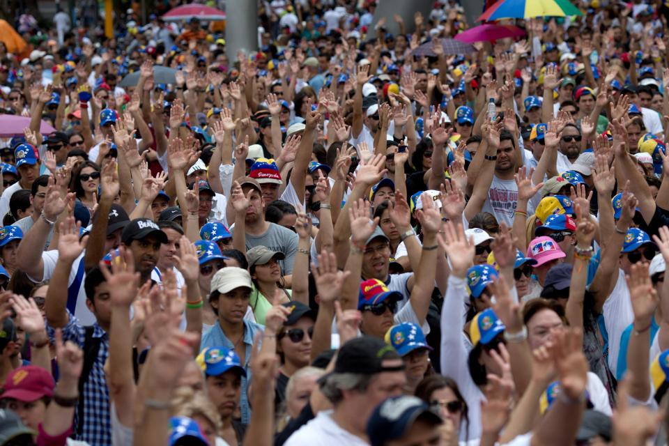 Demonstrators raise their arms in solidarity during a rally with human rights activists, in Caracas, Venezuela, Friday, Feb. 28, 2014. The start of a weeklong string of holidays leading up to the March 5 anniversary of former President Hugo Chavez's death has not completely pulled demonstrators from the streets as the government apparently hoped. President Nicolas Maduro announced this week that he was adding Thursday and Friday to the already scheduled long Carnival weekend that includes Monday and Tuesday off, and many people interpreted it as an attempt to calm tensions. (AP Photo/Rodrigo Abd)