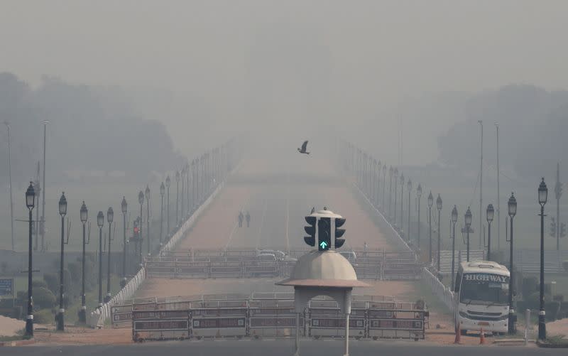 FILE PHOTO: People walk near India Gate on a smoggy morning in New Delhi