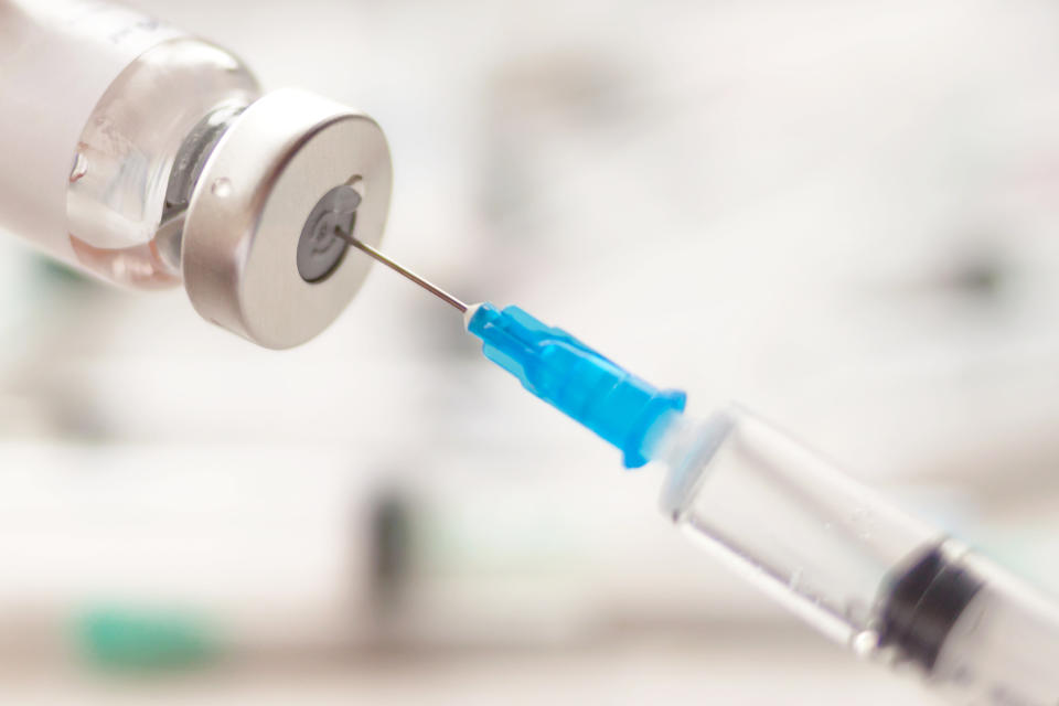 Dialing medicine into syringe from glass bottle. Ampoule and syringe needle close-up. Selective soft focus. Text copy space