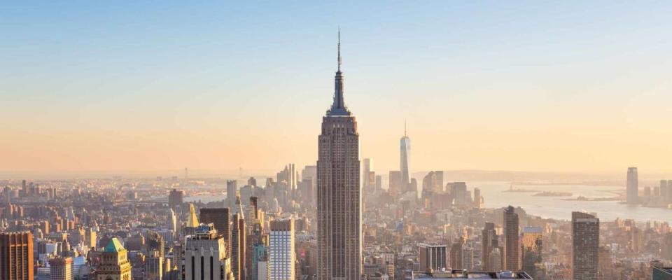 New York City. Manhattan downtown skyline with illuminated Empire State Building and skyscrapers at sunset.