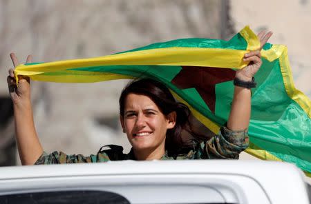 A female fighter of Syrian Democratic Forces waves a flag while onboard a pick up truck in Raqqa, Syria October 18, 2017. REUTERS/Erik De Castro