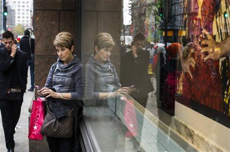 A woman stops to use her phone in front of holiday window displays at Macy's flagship store in New York, November 22, 2013. REUTERS/Lucas Jackson