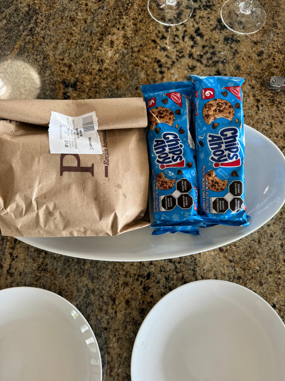 A white plate with two packs of Chips Ahoy! cookies and a brown paper sandwich bag with the receipt attached on a countertop