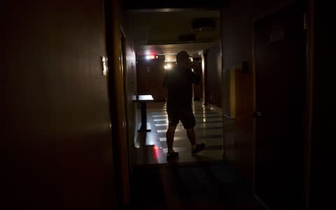 A guest walks toward the lobby of a hotel illuminated by emergency lights following a power outage in Tampa, Florida - Credit: Bloomberg