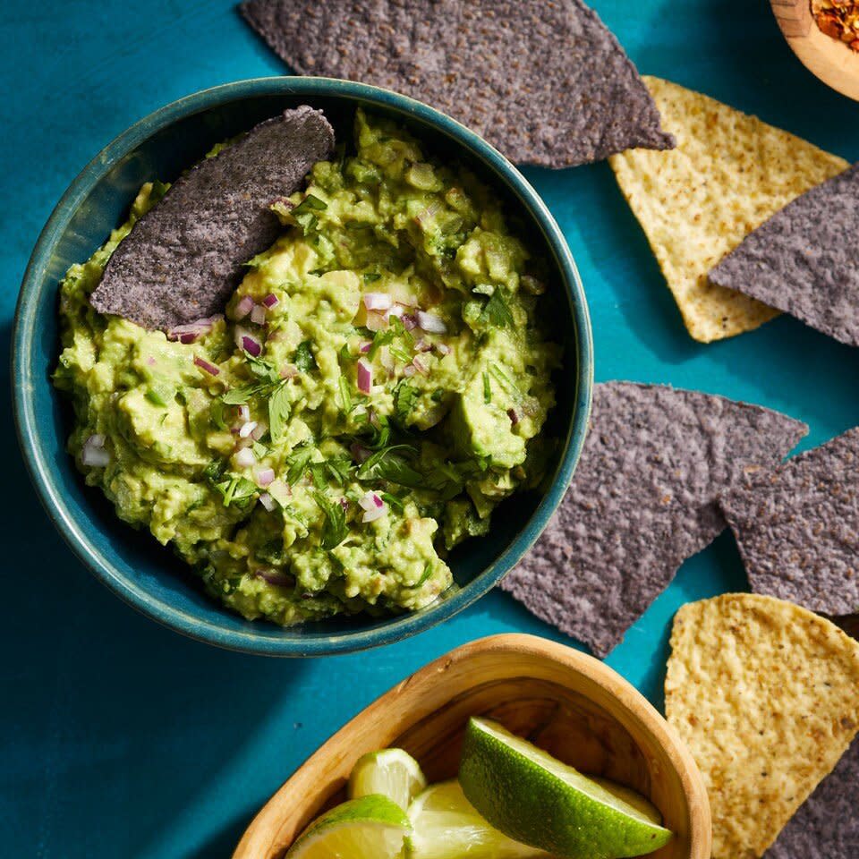 overhead shot of Almost Chipotle's Guacamole in blue bowl on blue background with chips