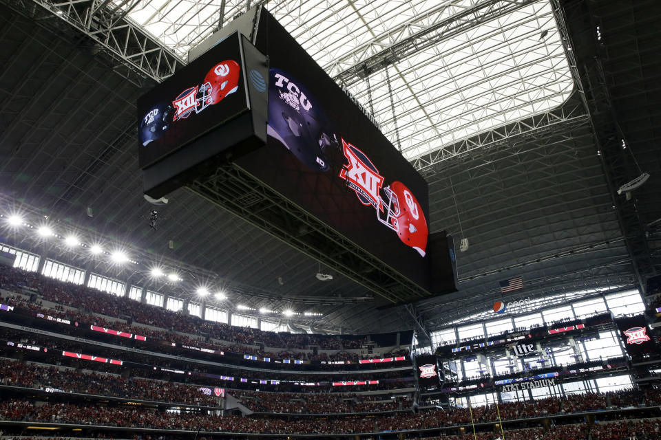 FILE - In this Dec. 2, 2017, file photo, the video screen inside AT&T Stadium displays the TCU and Oklahoma logo's during the first half of the Big 12 Conference championship NCAA college football game in Arlington, Texas. The Big 12 has extended membership invitations to BYU, UCF, Cincinnati and Houston to join the Power Five league. That comes in advance of the league losing Oklahoma and Texas to the Southeastern Conference. (AP Photo/Tony Gutierrez, File)