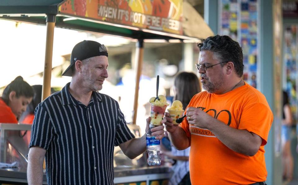 Dan Binstone, left, and Javier Arau, toast with their Merlino’s freezes on June 21 at Sutter Health Park in West Sacramento.