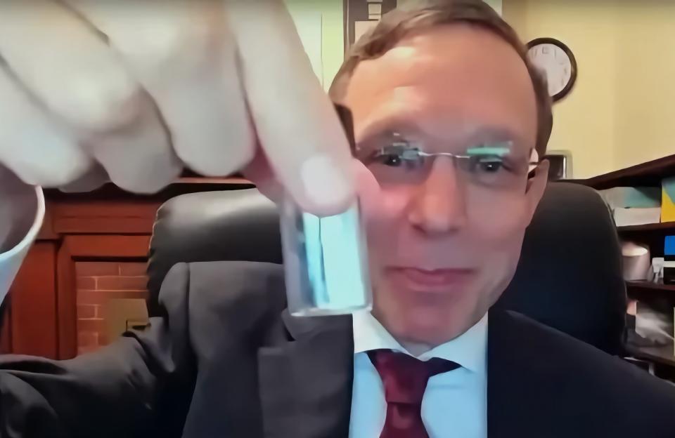 Harvard astrophysicist Avi Loeb holding a vial while looking at the camera with a proud smile.