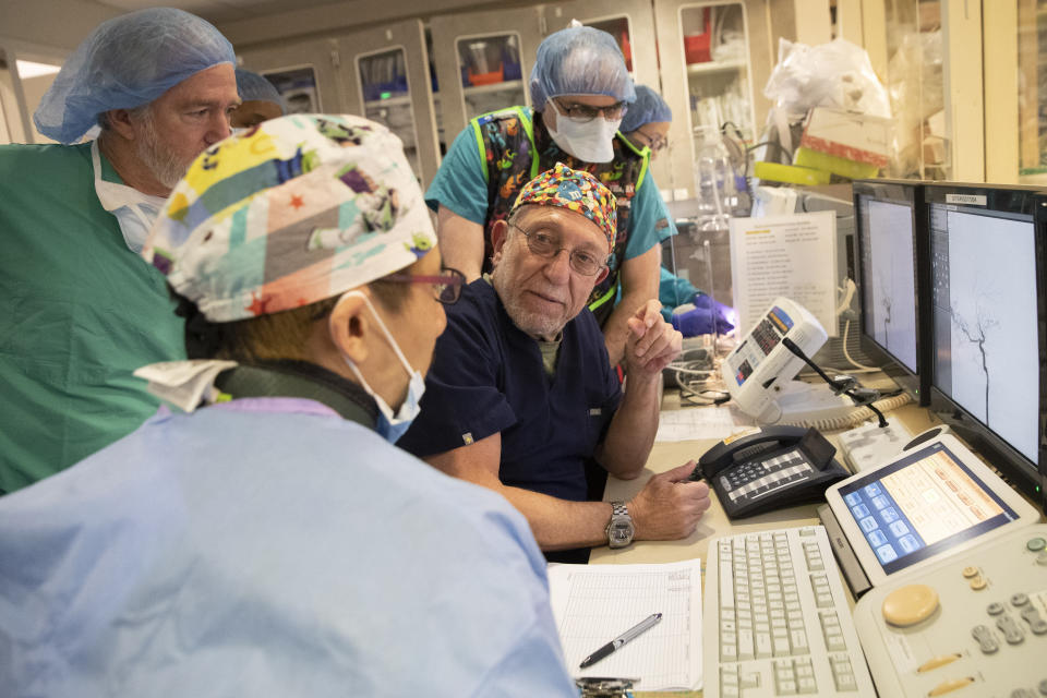 El doctor Alejandro Berenstein, en el centro, habla con el neuroradiólogo Tomoyoshi Shigematsu, al frente, y los médicos Joel Schneider, a la izquierda y Omar Kass-Hout, a la derecha, antes de operar a Omar Patzán el 26 de febrero del 2020 en el hospital Mount Sinai de Nueva York. (AP Photo/Mary Altaffer)