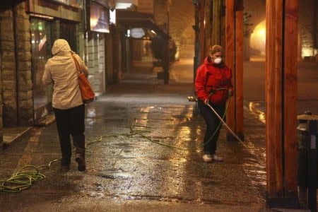 Residents wash a sidewalk covered with ashes from Calbuco in San Carlos de Bariloche. REUTERS/Chiwi Giambirtone