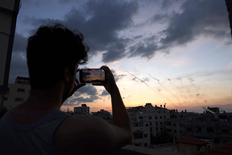 A man records a video with his mobile phone of rockets being fired from Gaza City towards Israel on October 7.