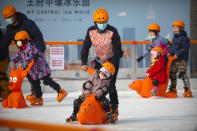 People wearing face masks to prevent the spread of the coronavirus skate at an outdoor ice skating rink in Beijing, Saturday, Jan. 23, 2021. (AP Photo/Mark Schiefelbein)