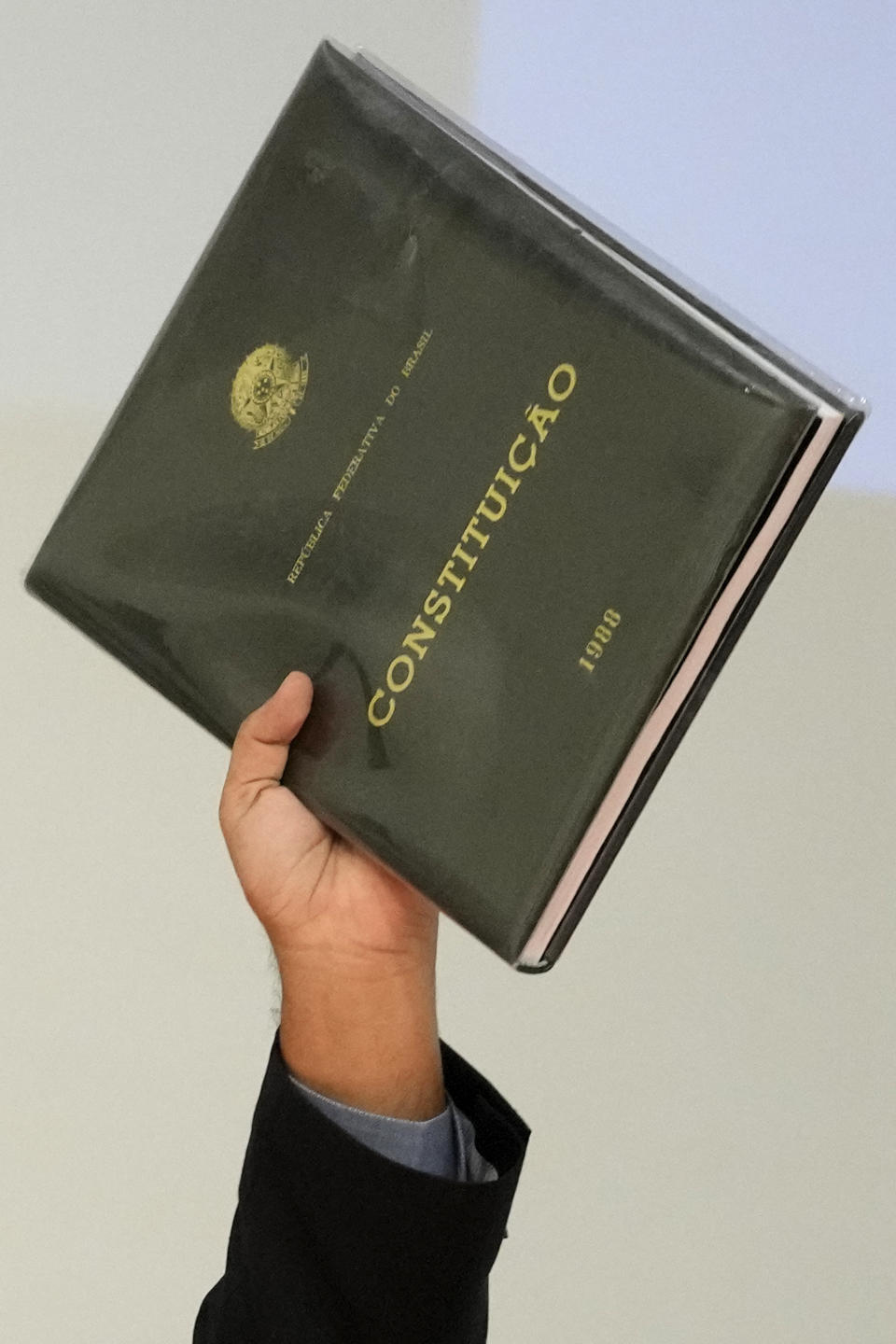 Justice Minister Flavio Dino holds up a historic edition of the 1988 Brazilian Constitution that was removed from the Supreme Court building when stormed by supporters of former President Jair Bolsonaro, during a tribute to security professionals who worked to defend public buildings, at the Justice Ministry in Brasilia, Brazil, Friday, Jan. 13, 2023. Rioters invaded government buildings in the capital on Jan. 8. (AP Photo/Eraldo Peres)