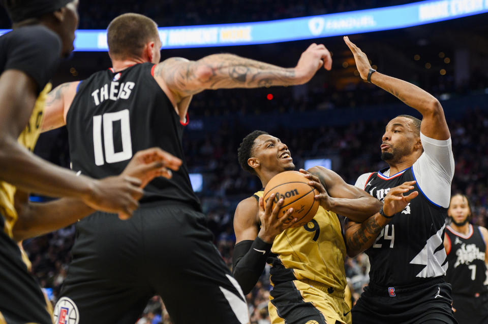 Toronto Raptors guard RJ Barrett (9) goes to the basket while defended by Los Angeles Clippers guard Norman Powell (24) and center Daniel Theis (10) during the second half of an NBA basketball game in Toronto, Friday, Jan. 26, 2024. (Christopher Katsarov/The Canadian Press via AP)