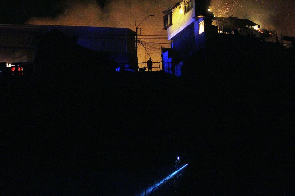 CORRECTS DAY OF WEEK - A man watches as a forest fire reaches urban areas in Valparaiso, Chile, Sunday April 13, 2014. Authorities say the forest fire has destroyed at least 150 homes and is forcing evacuations.( AP Photo/ Luis Hidalgo)