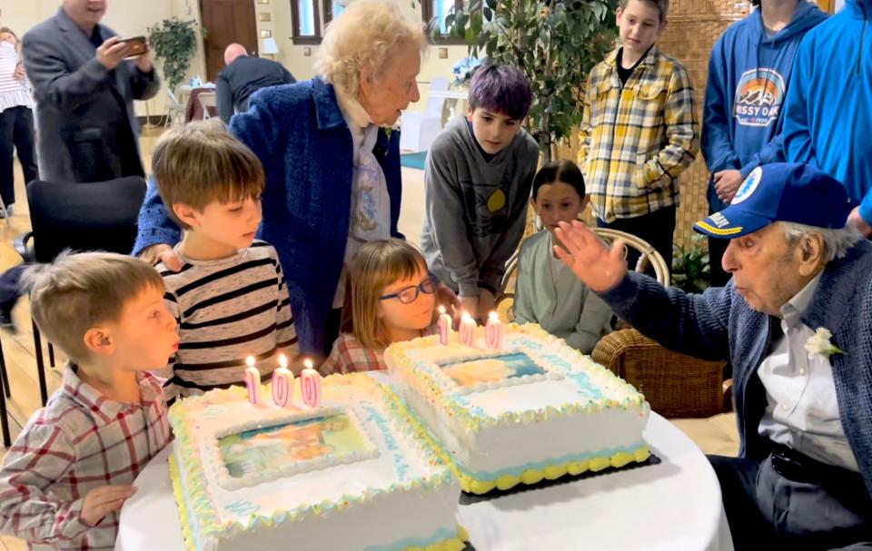 WWII bomber pilot John Stellitano blows out the candles on his 100th birthday cake, assisted by some of his 16 great-grandchildren. (That number went up to 17 a few days later when granddaughter Colby [Ladd] Telford gave birth to a son, Lenox.)