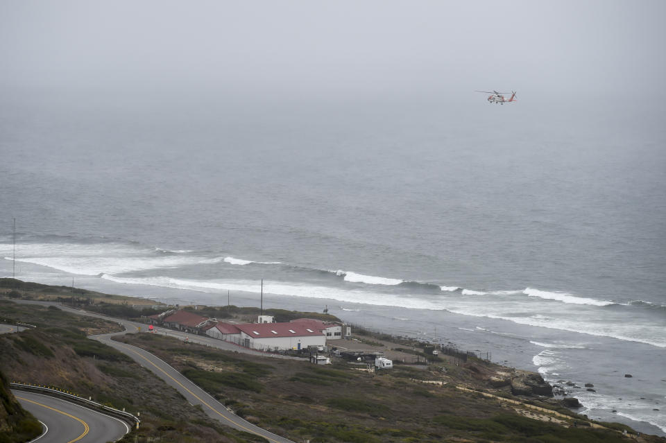 A U.S. Coast Guard helicopter flies over boats searching the area where a boat capsized just off the San Diego coast Sunday, May 2, 2021, in San Diego. (AP Photo/Denis Poroy)