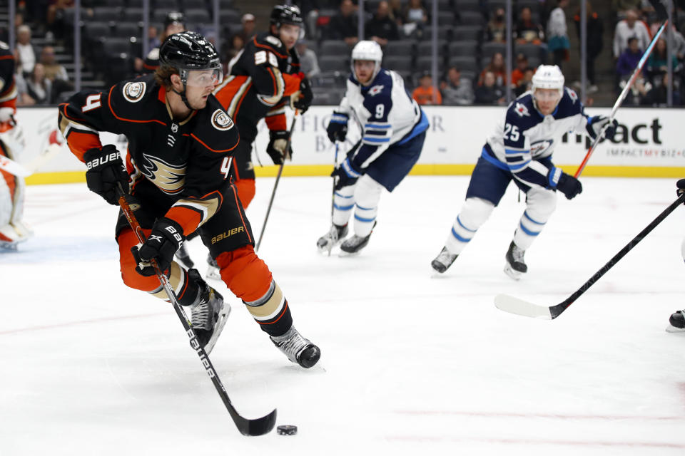 Anaheim Ducks defenseman Cam Fowler, left, controls the puck away from Winnipeg Jets centers Andrew Copp (9) and Paul Stastny (25) during the first period of an NHL hockey game in Anaheim, Calif., Wednesday, Oct. 13, 2021. (AP Photo/Alex Gallardo)
