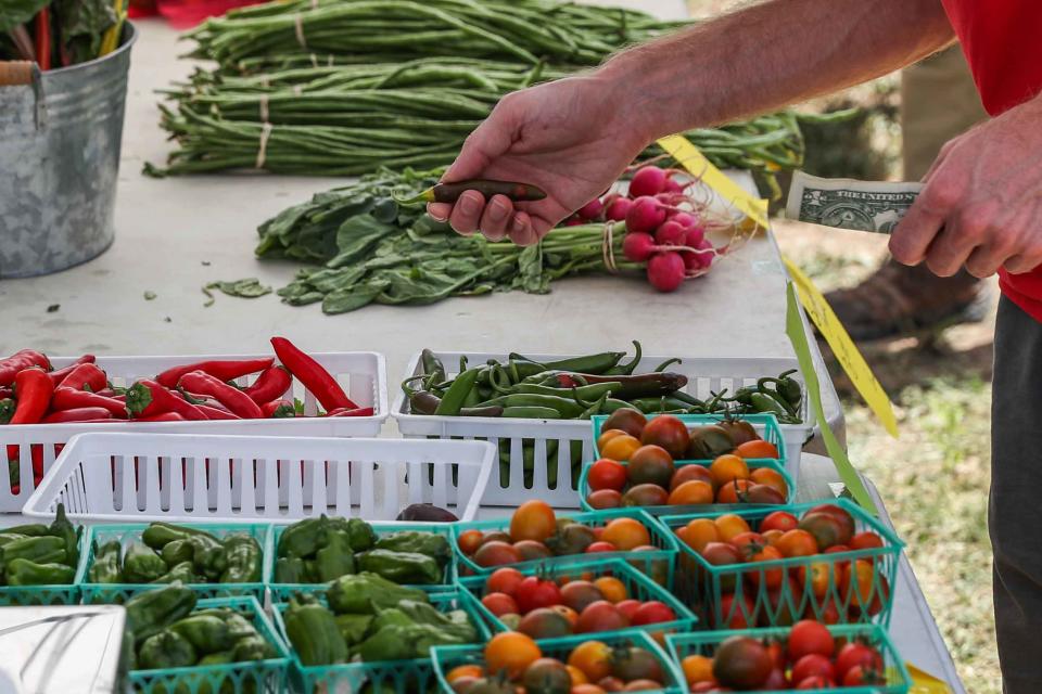 Tyler Merriman selects some vegetables from the Flintrock Hill Farm stand at the SFC Farmers' Market at Burger Center's parking lot. Healthful, unprocessed foods, including fresh vegetables, are recommended to reduce heart disease risks.