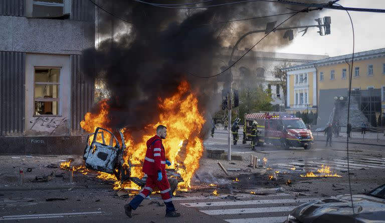 Un trabajador médico pasa junto a un automóvil en llamas después de un ataque ruso en Kiev, Ucrania, el lunes 10 de octubre de 2022