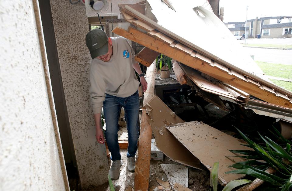 Dylan Sherfield walks through a damaged room in his home, Thursday, April, 20, 2023, in Shawnee, Okla., after tornado moved through the area Wednesday night in Shawnee, Okla.