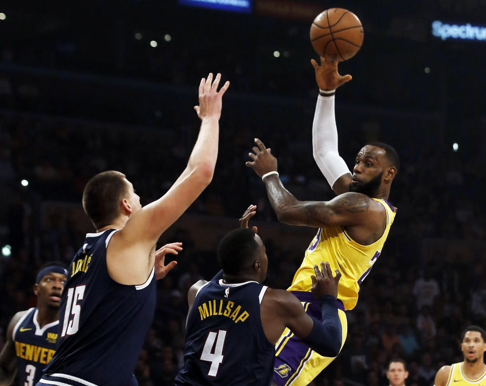 Los Angeles Lakers forward LeBron James, right, passes over Denver Nuggets center Nikola Jokic (15), of Serbia, and forward Paul Millsap (4) during the first half of an NBA basketball game in Los Angeles, Thursday, Oct. 25, 2018. (AP Photo/Alex Gallardo)