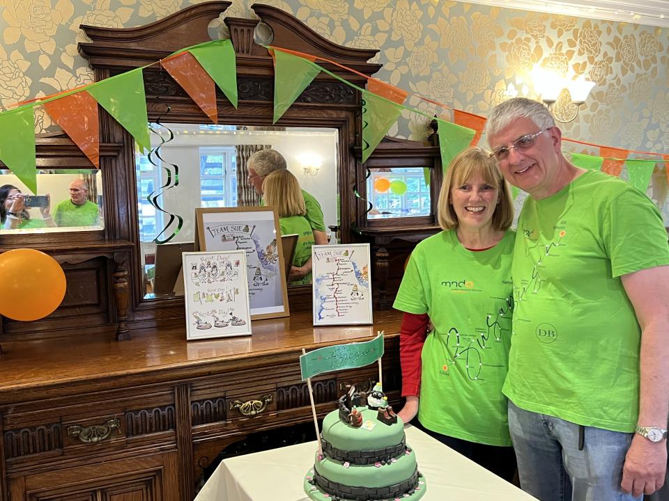 Susan Fletcher Watts and husband Brian with cake wearing green charity tops