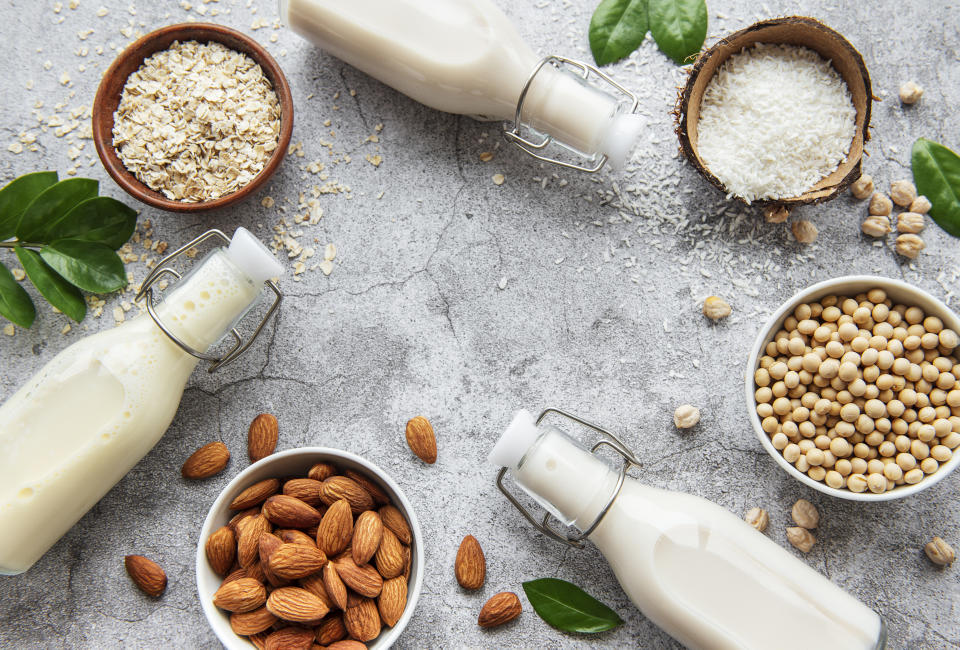 Alternative types of vegan milks in glass bottles on a  concrete background. Top view