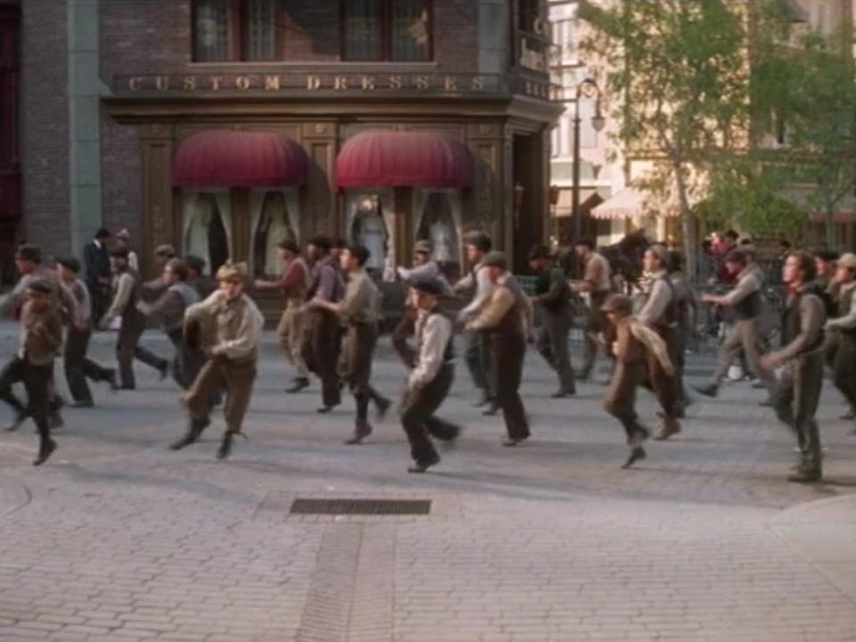 a dance scene in newsies with paperboys in the air dancing