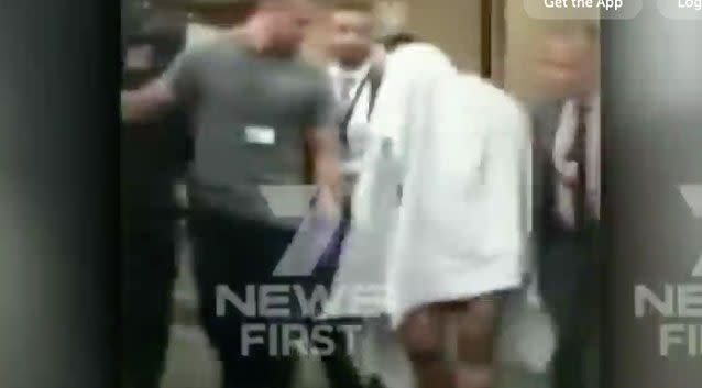 TV footage shows a man with a bandage on his head and draped in a blanket being led away by authorities after the arrests overnight. Photo: 7 News