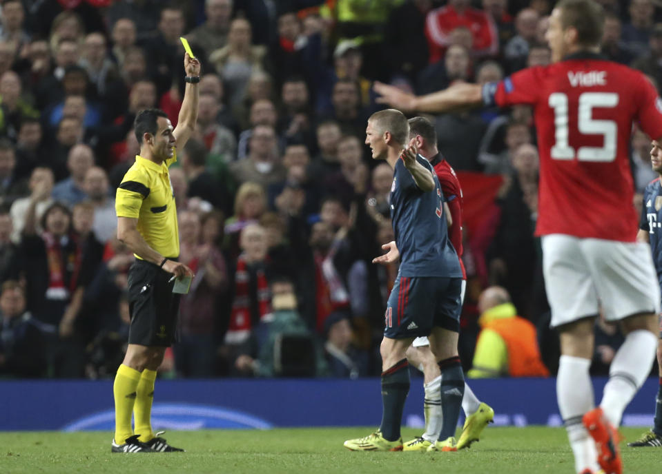 Bayern's Bastian Schweinsteiger is booked by referee Carlos Velasco Carballo from Spain, left, during the Champions League quarterfinal first leg soccer match between Manchester United and Bayern Munich at Old Trafford Stadium, Manchester, England, Tuesday, April 1, 2014.(AP Photo/Jon Super)