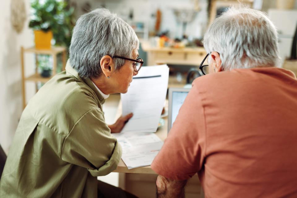 A senior couple goes over paperwork at the kitchen table.